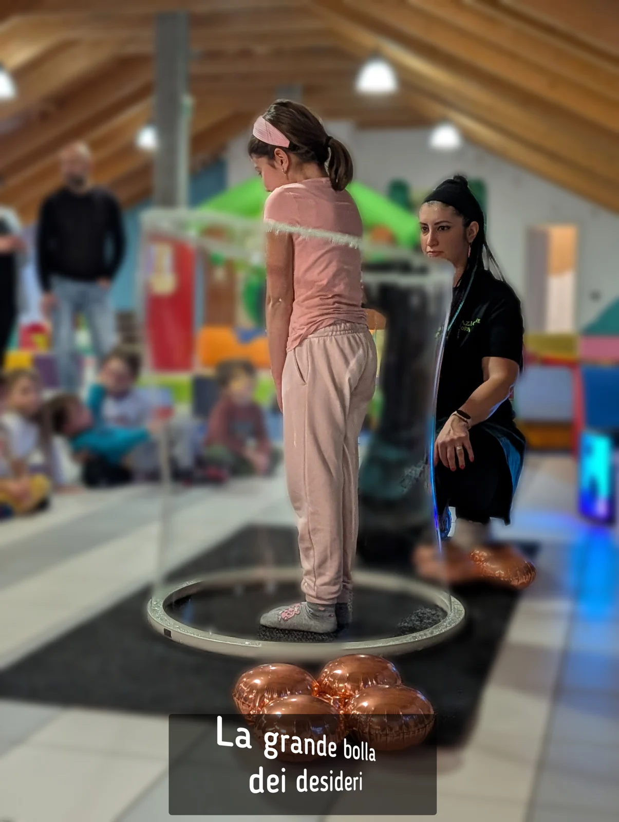 Animatrice e bambina durante un gioco con una bolla di sapone gigante
