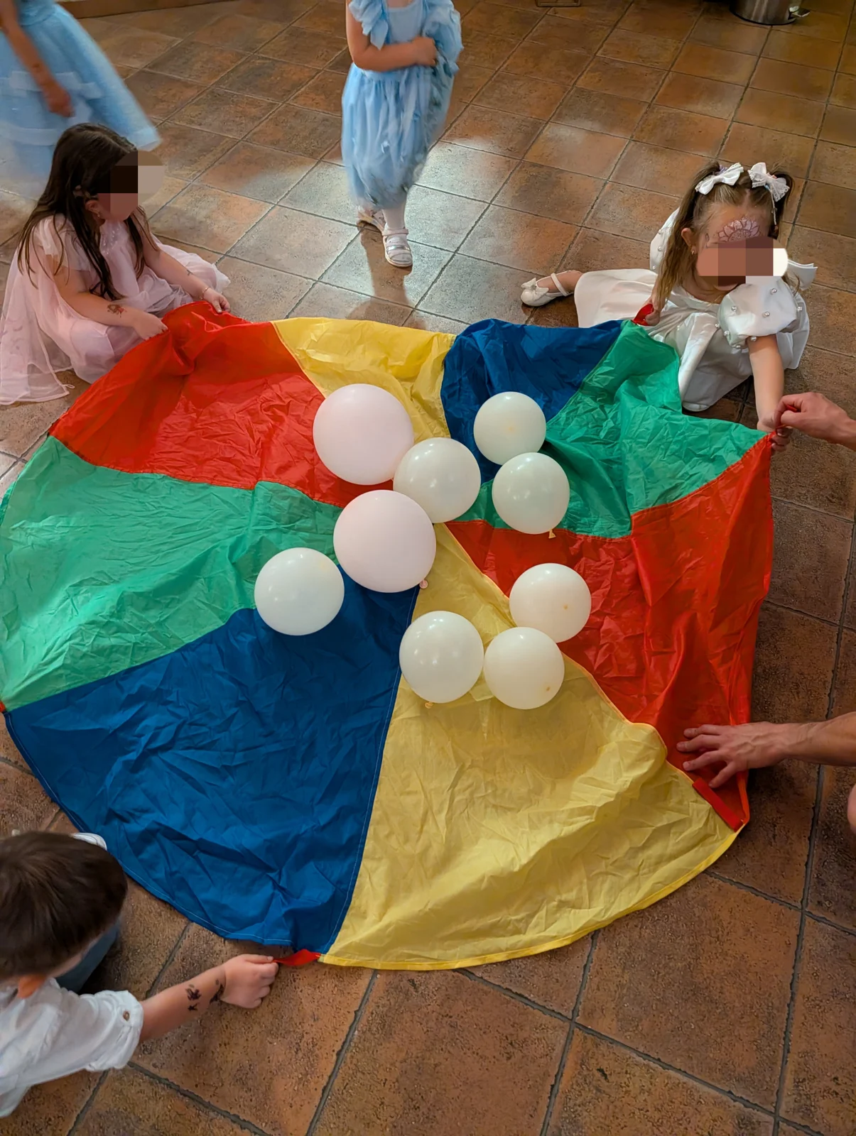 Bambini che giocano insieme con un telo multicolore e palloncini